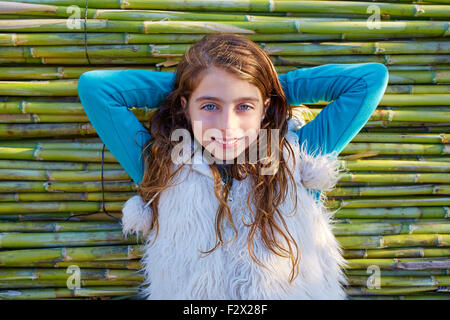 Kid girl relaxed in green canes background in autumn winter Stock Photo