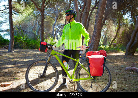MTB Biker Bicycle touring in a pine forest with pannier racks and saddlebag Stock Photo