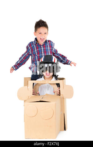 Adorable young boys playing and sitting in a cardboard car isolated over white background Stock Photo