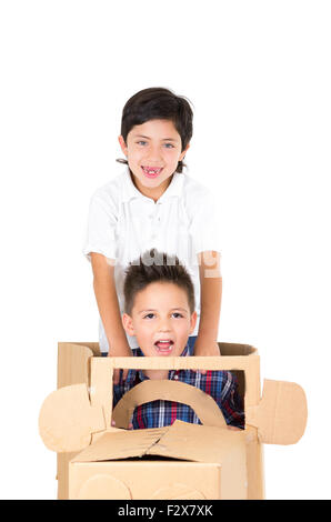 Adorable young boys playing and sitting in a cardboard car isolated over white background Stock Photo