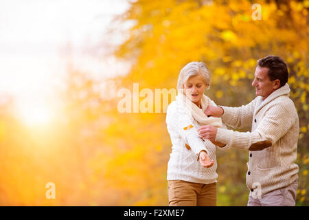 Active seniors having fun and playing with the leaves in autumn forest Stock Photo