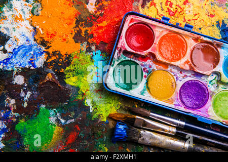 Desk of an artist with watercolor paints and paintbrushes.