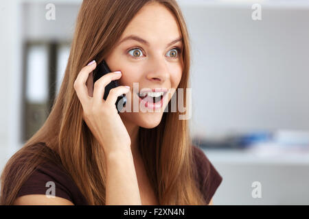 Portrait of young surprised business woman talking on phone. Stock Photo