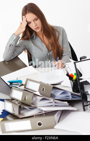 Portrait of young beautiful business woman surrounded by big pile of documents. Stock Photo