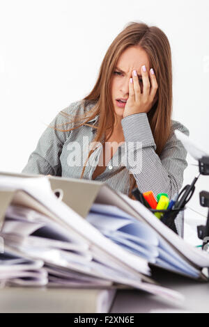 Portrait of young beautiful business woman surrounded by big pile of documents. Stock Photo