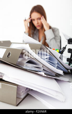 Portrait of young beautiful business woman surrounded by big pile of documents. Stock Photo