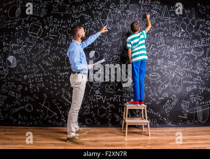 Young hipster school teacher with his pupil in front of big blackboard Stock Photo