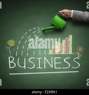 Watering can and word business drawn on a blackboard concept for business growth, investment, savings and making money Stock Photo