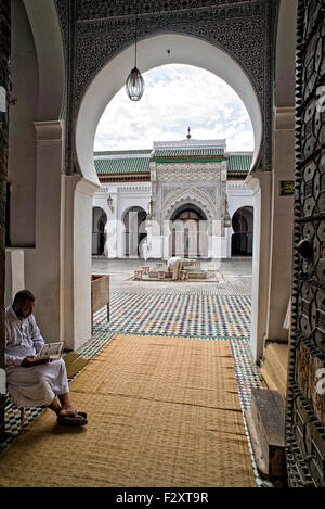 Man reading the Quran in the entrance of the Kairaouine mosque, Fes, Morocco Stock Photo