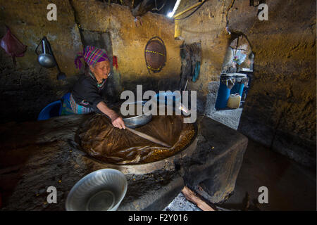 Woman of the black Hmong hill tribe in Vietnam brewing alcohol in her house Stock Photo
