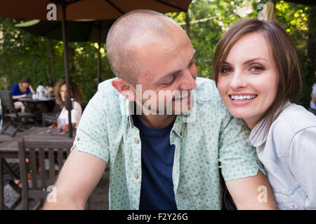 A young man and woman, a couple seated together outside at a cafe. Stock Photo