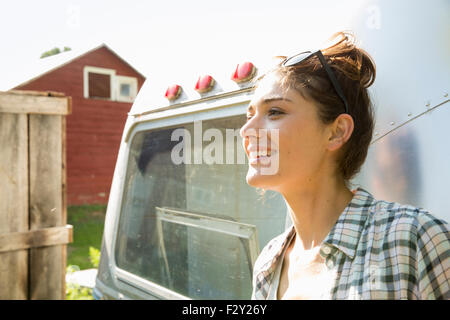 A young woman wearing sunglasses by a silver coloured trailer. Stock Photo