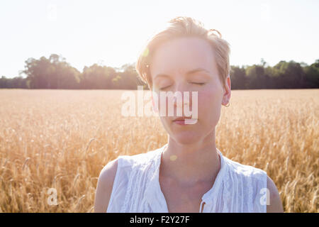 Head and shoulders portrait of a young woman standing in a cornfield. Stock Photo