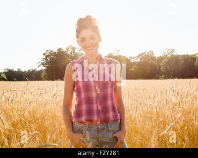 A young woman standing in a field of tall ripe corn. Stock Photo
