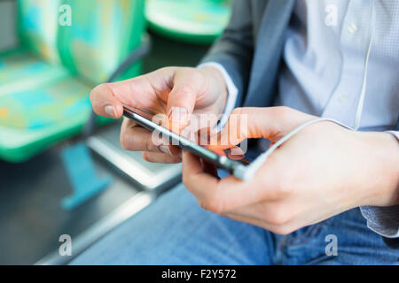 Man texting sms, using cell phone apps. video gaming on bus. Close-up hands Stock Photo
