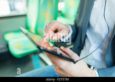 Man listening music with tablet pc. on bus. texting message. Close-up hands Stock Photo
