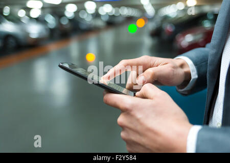 In parking car a man using his mobile phone.  Light bokeh background Stock Photo