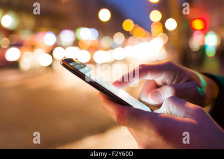 Man using his Mobile Phone in the street, night light bokeh Background Stock Photo