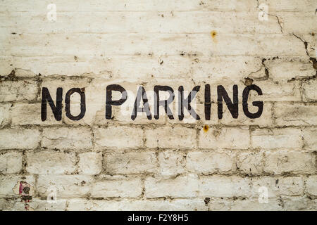 No Parking sign hand painted in black on a white brick wall Stock Photo