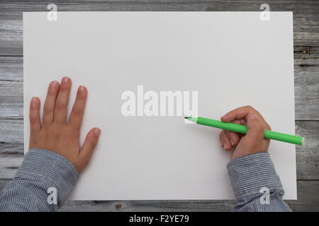 kid holding pen on blank sheet of paper Stock Photo