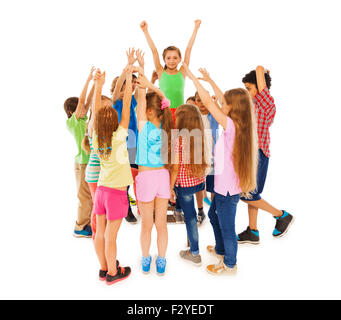 Class leader girl raised hands in circle of mates Stock Photo