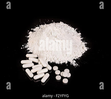 drug powder tablets and capsules close-up on black background. Stock Photo