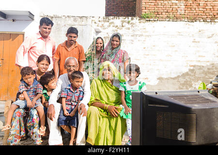 indian group crowds rural villager Joint Family home sitting Charpai and watching Television Stock Photo