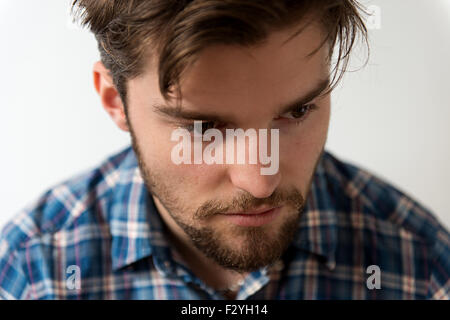 Close up image with shallow depth of field of a handsome young man. He is wearing a casual blue checked shirt and has a beard Stock Photo