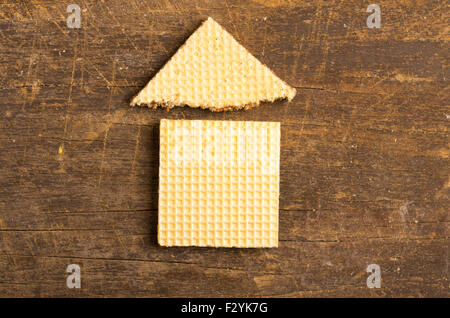 Simple house design illustrated by using rectangular and a triangular cookie on wooden surface. Stock Photo