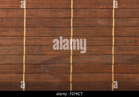 Bamboo wooden dark brown used wicker braided mat with light yellow thread background Stock Photo