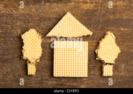 Simple house design illustrated by using rectangular and a triangular cookie on wooden surface. Stock Photo