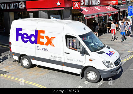 Aerial view looking down on white Fedex express parcels delivery van with brand logo & driver in sunny shopping street scene Strand London England UK Stock Photo