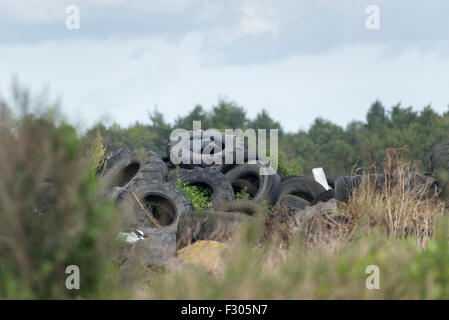 large pile of used and discarded rubber vehicle tyres dumped on wasteland in the uk