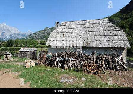 A stone farm house with a traditional shingled roof in the community of Teth. Firewood for the winter is piled up under the eave Stock Photo