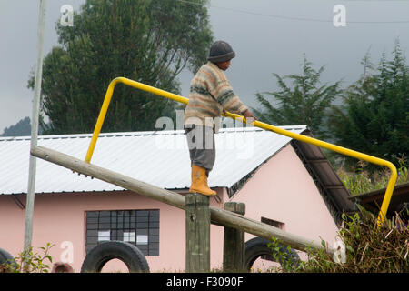 Boy playing on teeter-totter in schoolyard, Machachi, Ecuador Stock Photo