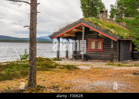 Cabin with turf roof with a lake in the background in Norway Stock Photo