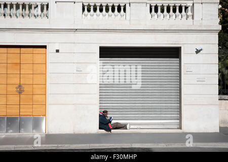 Homeless in Rome. A homeless man sits in a shop doorway, Via Nazionale, Rome, Italy. Stock Photo