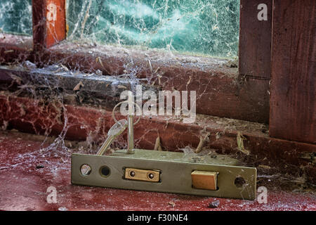 Door locking mechanism with keys on a window ledge covered in cobwebs Stock Photo