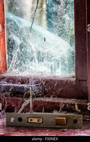 Door locking mechanism with keys on a window ledge covered in cobwebs Stock Photo