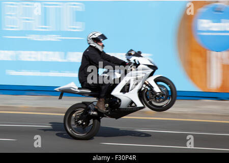 Liverpool, Merseyside, UK  27th September, 2015. Motorcyclist wheelies, moving, movement, uk roads popping a wheelie on the Strand as Police register concern about speeding drivers.  Statistics have been released for the number of drivers allegedly clocking up 100mph or more on local roads in the last 12 months. The statistics worry police, who say the number of motorists caught speeding is only the tip of the iceberg. Warrants have been issued as police clamp down on dangerous and anti-social use of bikes across the area in Merseyside. Stock Photo