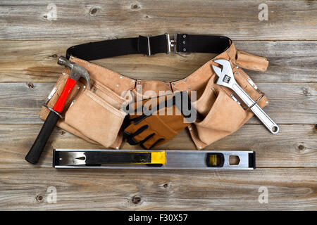 Traditional leather tool belt with tools on rustic wooden floor. Stock Photo