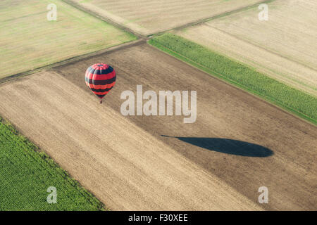 Aerial view of an hot air balloon and its shadow nearly grounded over fields Stock Photo