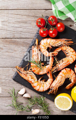 Grilled shrimps on stone plate over wooden table. Top view with copy space Stock Photo