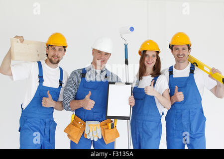 Group of smiling builders in hardhats with tools indoors Stock Photo