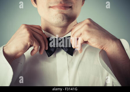 Closeup on a happy young man tying a bow tie Stock Photo