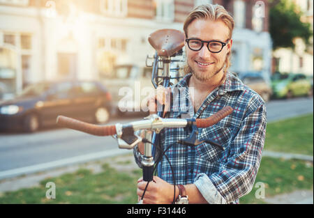 Young Man City Lifestyle. Carrying bike on his shoulder. Smiling portrait Stock Photo