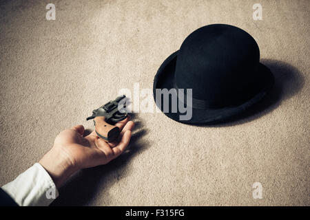 A man is lying dead on the floor with his hat and his revolver Stock Photo