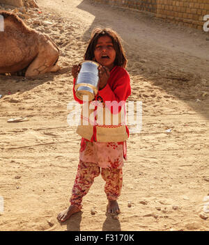 A poor Indian girl child looking sad holding utensil in hand in Khuri, Jaisalmer, Rajasthan Stock Photo