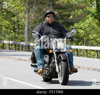 Fat obese motorcycle rider riding past graffiti on Southend seafront ...
