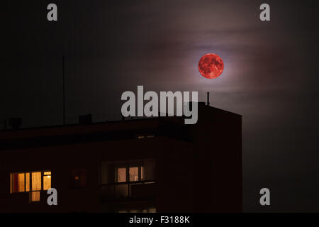 Red full moon in red color also called bloodmoon on the background of building. Stock Photo